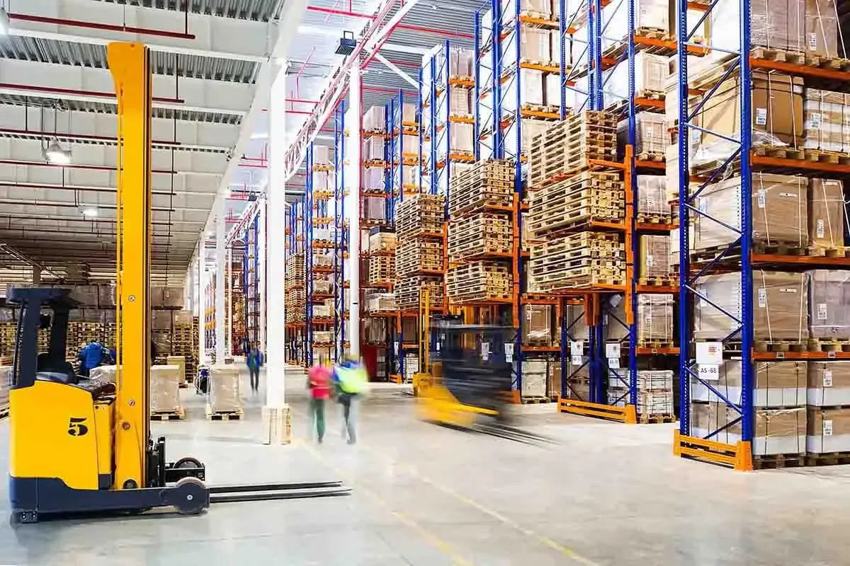 Industrial warehouse with pallets, boxes, forklifts, and workers
