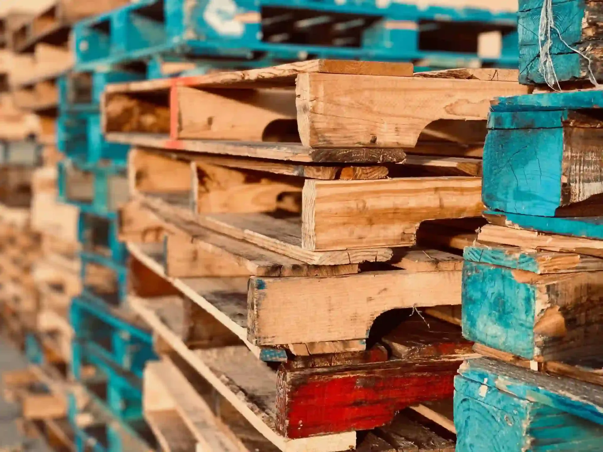 Stacks of recycled wooden pallets in varied colours